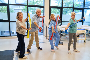 Elderly group performing therapeutic exercises with therapist in rehabilitation center