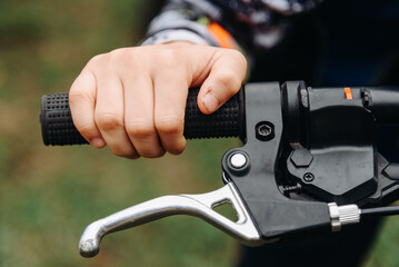 young boy hand on handlebars of bicycle, close up view, riding bike in park or forest