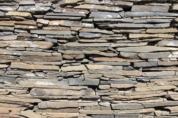 A wall made of thin and tall rubble stones. Stone wall detail for backgrounds.
