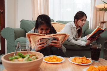 Asian Woman Friend Doing Lifestyle Indoor Smiling Phone Happiness, Sharing Joy and Memories Together at Home, Relaxing on Sofa with Smart Devices and Family Bonding Moments