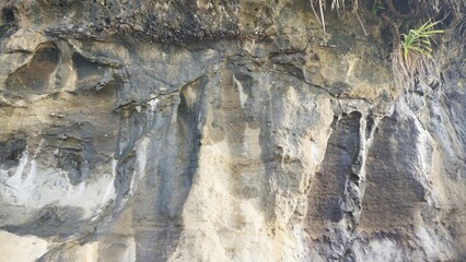 large rock with natural carvings on a cliff near the beach
