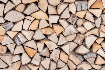 Selbstklebende Fototapeten A dense, textured wall of neatly stacked firewood logs, varying in size and shade of light brown and beige © Irwan
