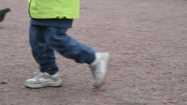 child runs along path in park, close-up view of legs, no face, unrecognizable