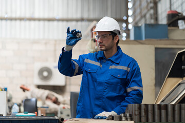 Male engineer worker inspecting quality parts of CNC machine in industrial factory, wearing safety...