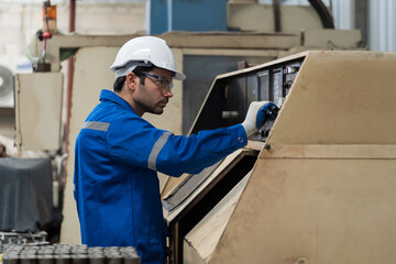 Male engineer worker inspecting quality parts of CNC machine in industrial factory, wearing safety uniform, glasses and hard hat. Technicians installing or replacing parts on CNC machines in factory