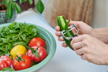 A woman washes fresh lemons, tomatoes, and leafy greens in a kitchen sink, preparing healthy ingredients near a sunlit window.