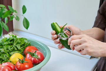 A woman washes fresh lemons, tomatoes, and leafy greens in a kitchen sink, preparing healthy ingredients near a sunlit window.