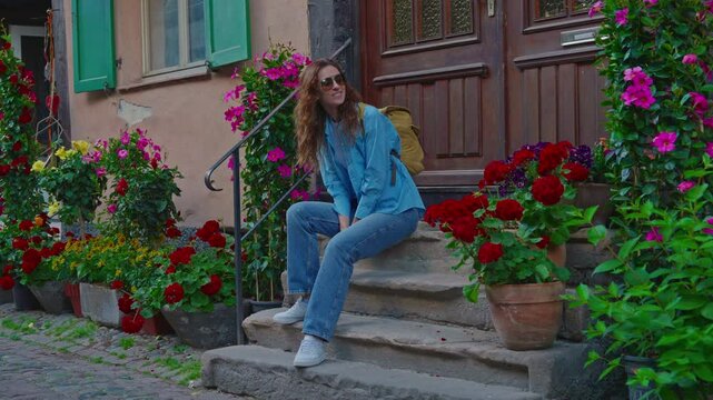 Woman on the beautiful street full of colorful houses with flowers of Eguisheim, France 