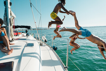 Happy multiracial friends jumping inside the ocean during summer vacation - Holidays and travel concept - Main focus on right man body