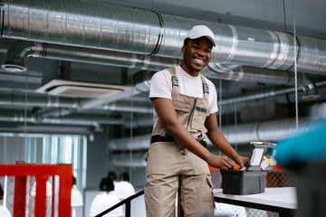 Skilled worker in a modern workspace smiles confidently while organizing tools during industrial setup