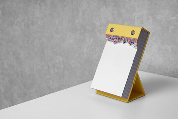 Blank vertical tear-off calendar on white desktop. Mockup. Office life. Planning, productivity, office supplies, journaling, writing and stationery design.