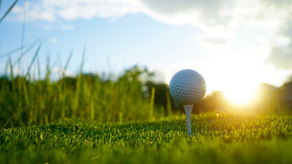 Golf ball on green grass in the evening golf course with sunshine background.