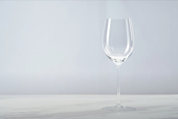 Empty wine glass placed on a white marble surface with a soft gray background, styled in a clean, minimal, and elegant studio setup