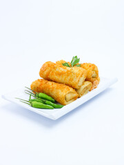 A plate of crispy golden vegetable risol served with green chili peppers and parsley garnish. isolated on white background. risol isolated