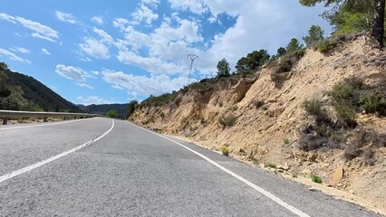 A scenic mountain road showcases a stunning blue sky and beautiful natural surroundings