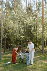 Couple setting up chairs in a vibrant forest during a sunny afternoon