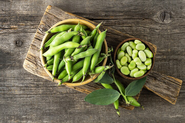 Fresh broad beans with pod in bowl on wooden background, healthy food