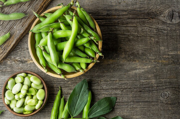 Fresh broad beans with pod in bowl on wooden background, healthy food