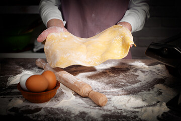 Baking concept. Caucasian female hands showing the stretched dough sheet.