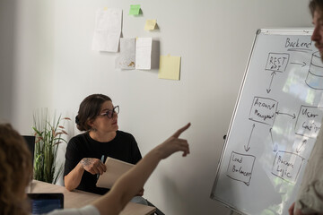 Three software developers brainstorming in a modern office. Team coding session with laptops...