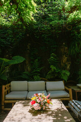 Sofa in lush garden with colorful spring flower arrangement