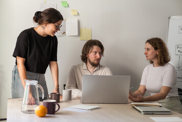 Three software developers brainstorming in a modern office. Team coding session with laptops...