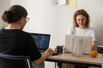 Three software developers brainstorming in a modern office. Team coding session with laptops...