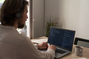 Three software developers brainstorming in a modern office. Team coding session with laptops...