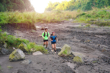 Asian Trail Runners Jogging on Rocky Path in Forested Mountain Area