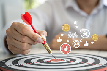 Businessman aiming a dart to a bullseye target achieving success and goals with focus
