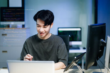 Asian developer writing code at night in modern office setup. Concept of software engineering, programming, digital workspace