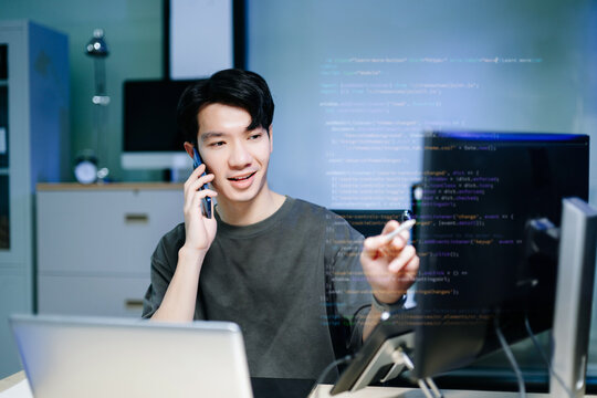Asian software developer working late with code on screens, tablet, and phone. Concept of programming, tech lifestyle,