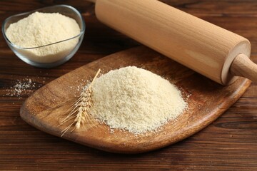Pile of flour, spike and rolling pin on wooden table, closeup