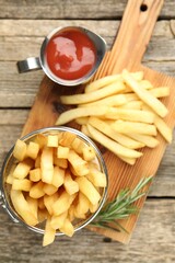 Tasty french fries served with ketchup and rosemary on wooden table, top view