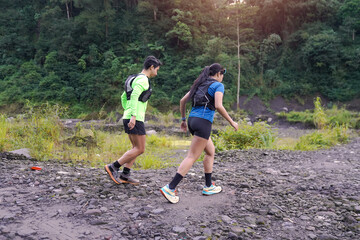 Back View of Trail Runners Jogging on Rocky Path in Forested Mountain Area