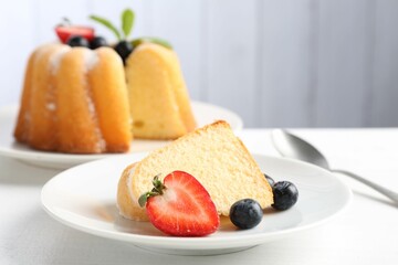 Tasty bundt cake with powdered sugar, berries and mint on white table, closeup