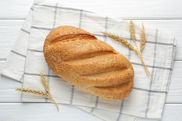 Fresh bread loaf and spikelets on white wooden table, flat lay