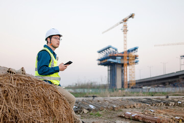 asian male engineer using smart phone in construction site