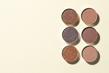 Beautiful eyeshadow refill pans on beige background, flat lay. Space for text