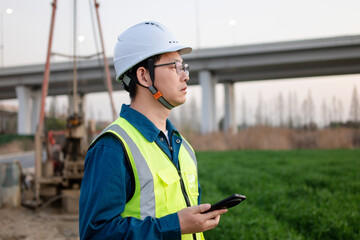 asian male engineer using smart phone in construction site