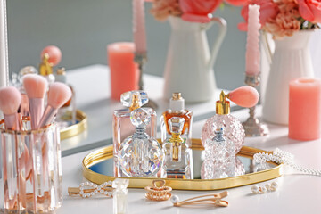 Bottles of different perfumes, accessories and flowers on dressing table indoors