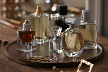 Bottles of different perfumes and accessories on wooden table, closeup