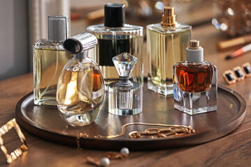 Bottles of different perfumes and accessories on wooden table, closeup