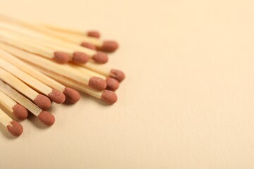 Matches with brown heads on beige background, closeup. Space for text