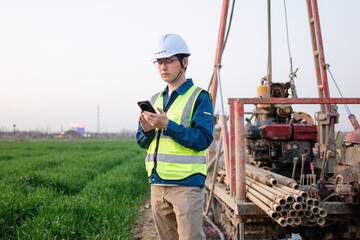 asian male engineer using smart phone in construction site