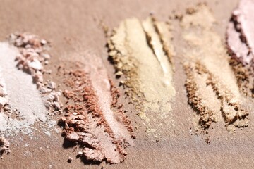 Different eyeshadows smudges on brown background, closeup