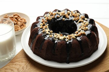 Delicious chocolate bundt cake with nuts and glass of milk on white wooden table, closeup