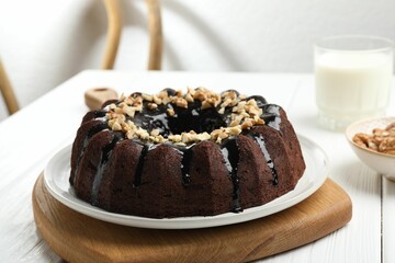 Delicious chocolate bundt cake with nuts on white wooden table indoors, closeup