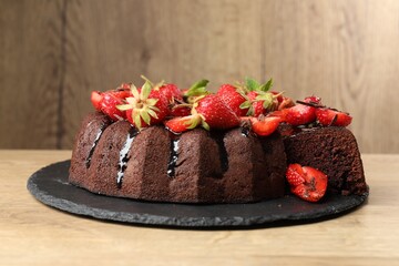 Delicious chocolate bundt cake with strawberries on wooden table, closeup