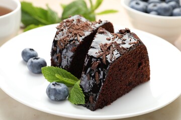 Pieces of delicious bundt cake with blueberries, mint, and chocolate shavings on table, closeup